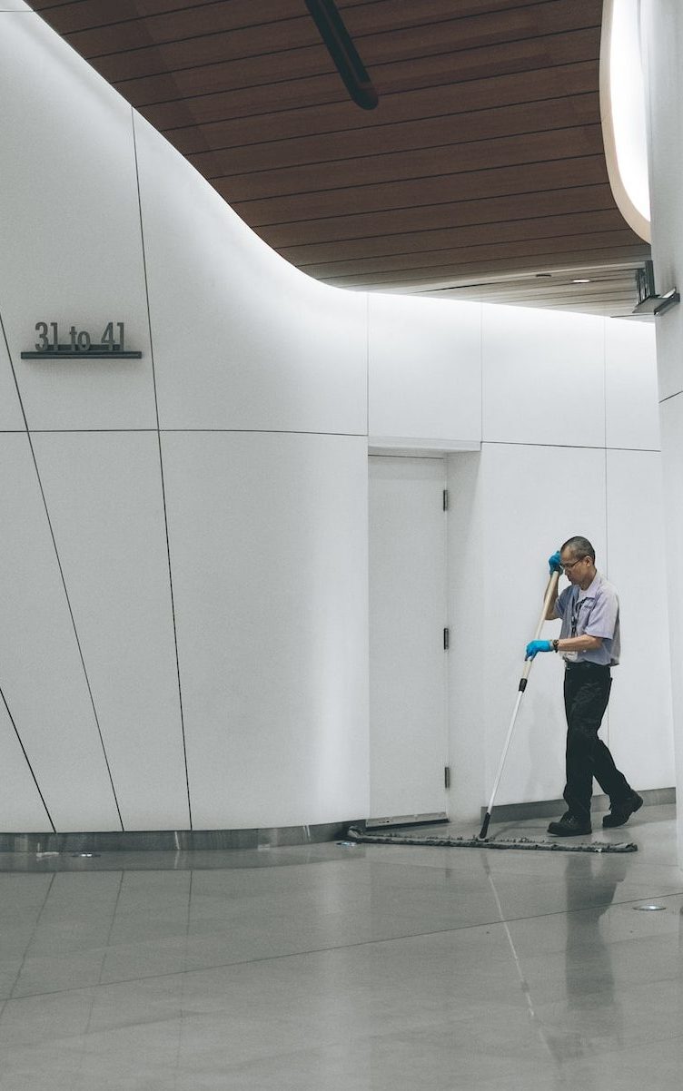 man cleaning on floor beside white wall